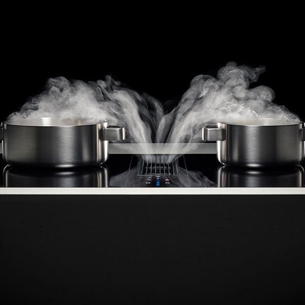 Image showcasing the Bora cooktop's advantage of ensuring fresh air and a clear view while cooking. Two stainless steel pots are placed on a Bora hob, with steam elegantly being drawn directly downward by the powerful, built-in extraction system, demonstrating its efficiency in vapour removal. This design ensures that the kitchen remains a clean, smoke-free environment, perfectly capturing Bora's commitment to a pleasant cooking atmosphere without the distraction of steam or cooking odours
