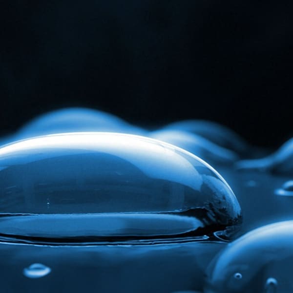 Image of smooth, rounded droplets on a surface, symbolising Bora's 'simple cleaning' advantage. The droplets reflect a deep blue hue, highlighting the non-stick, easy-to-clean nature of Bora's kitchen surfaces. This visual metaphor illustrates the effortless wipe-down process after cooking, underscoring the hassle-free maintenance of Bora's high-performance cooktops.